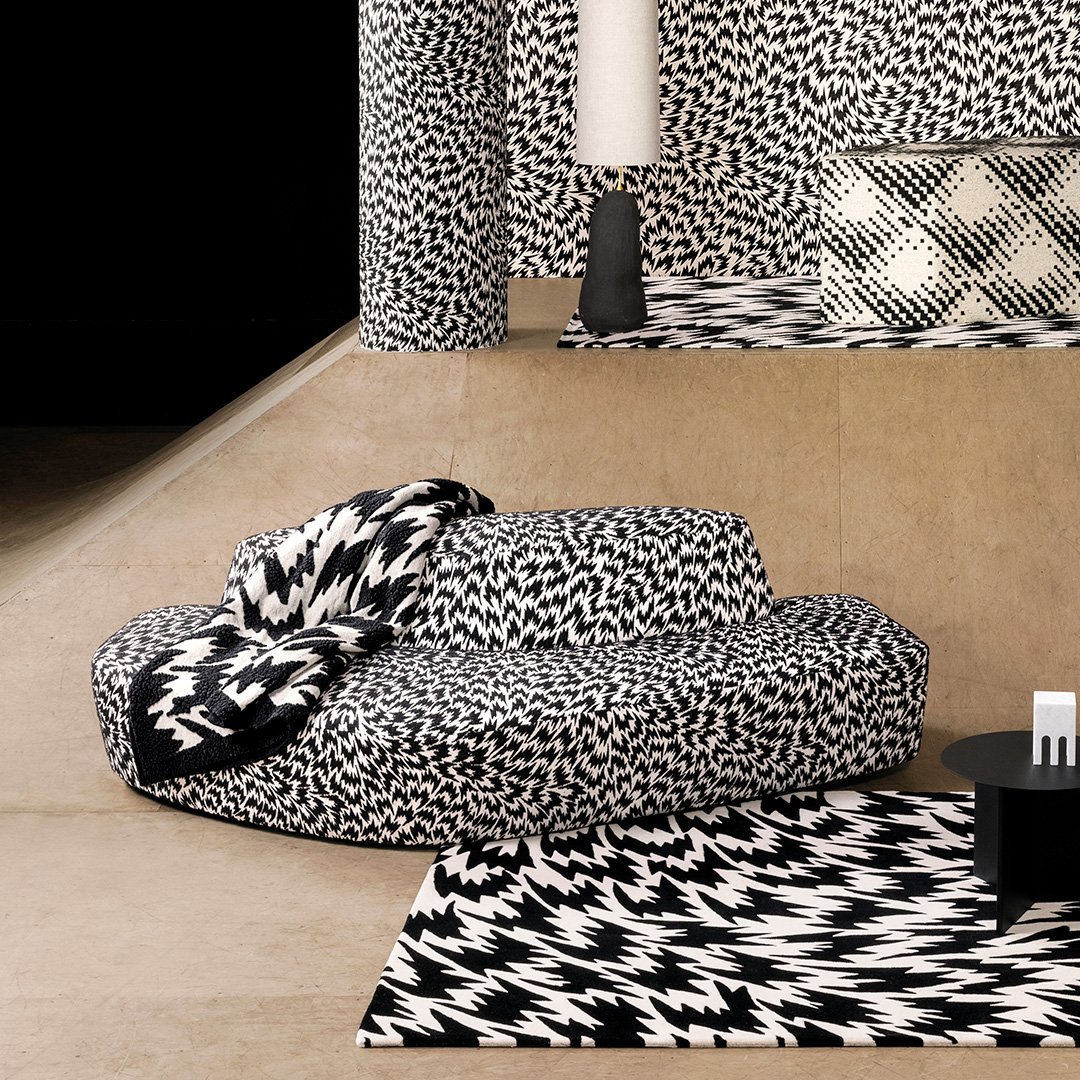 Tila, jossa on keskellä graafisella mustavalkoisella siksak-kuosilla verhoiltu sohva ja matto samalla kuviolla.
