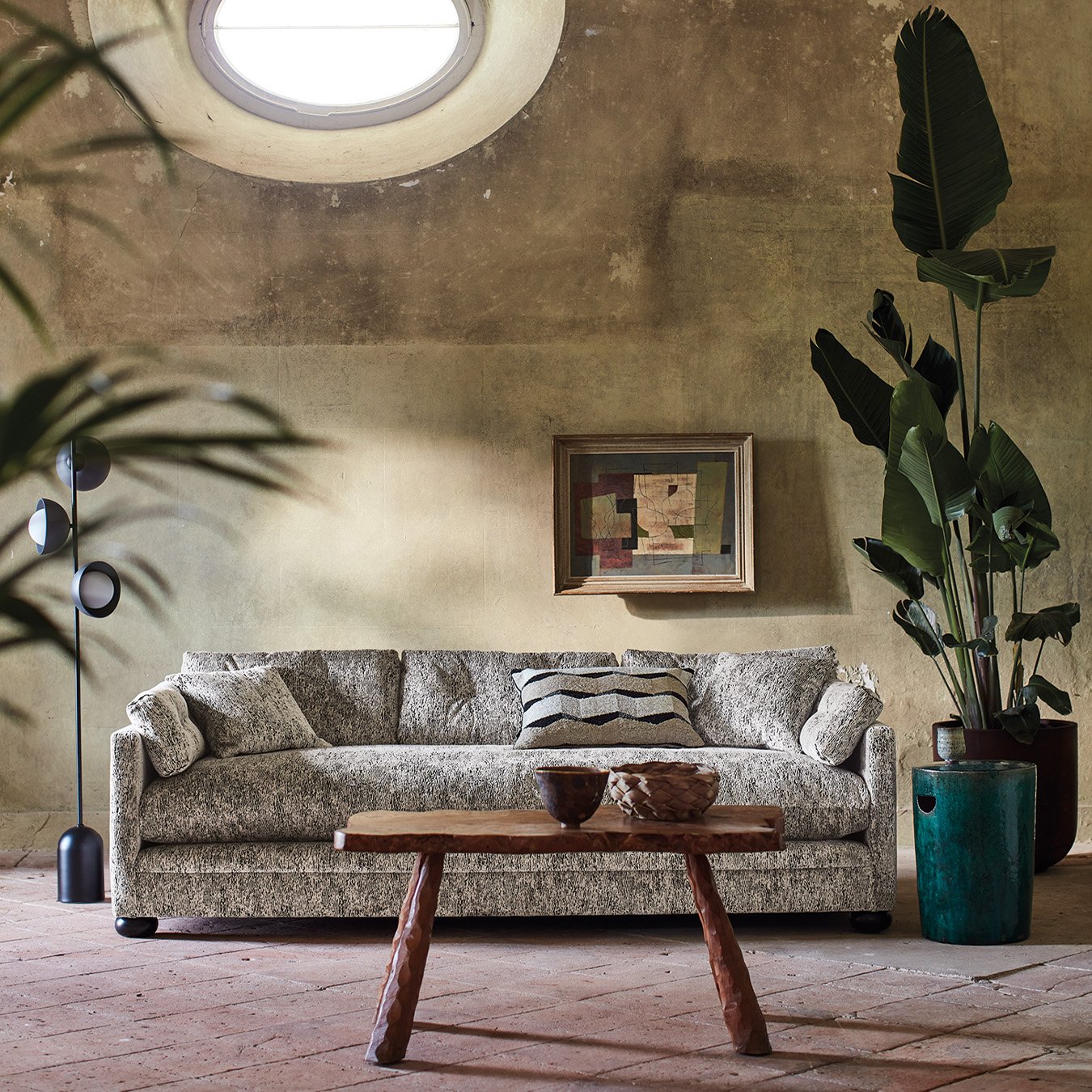 Sisustuskuva tilasta, jossa keskiössä vaalea struktuuripintainen sohva, sekä viherkasvit.