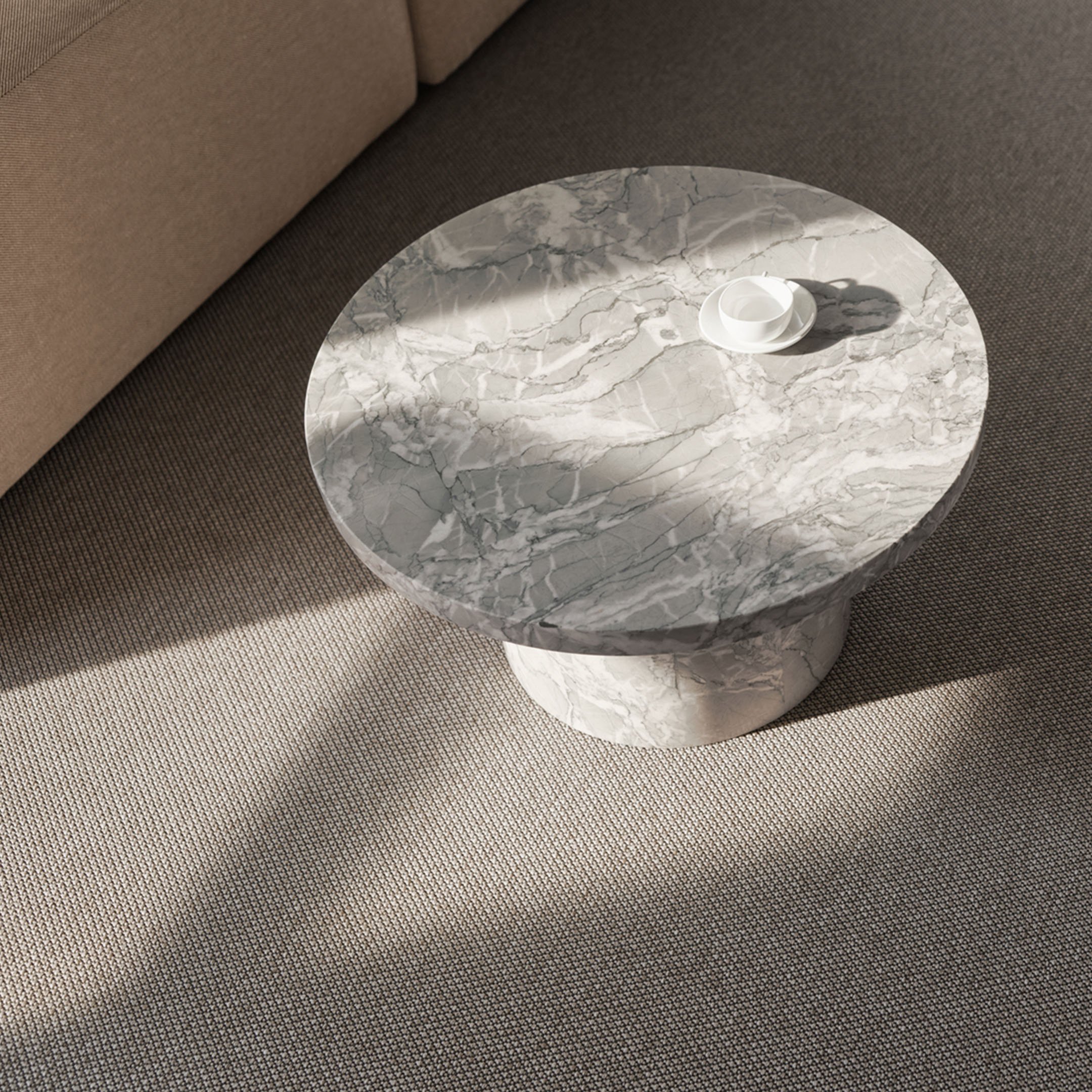 Lähikuva marmorisesta sivupöydästä, joka on sijoitettu beigen tekstiililattian päälle.